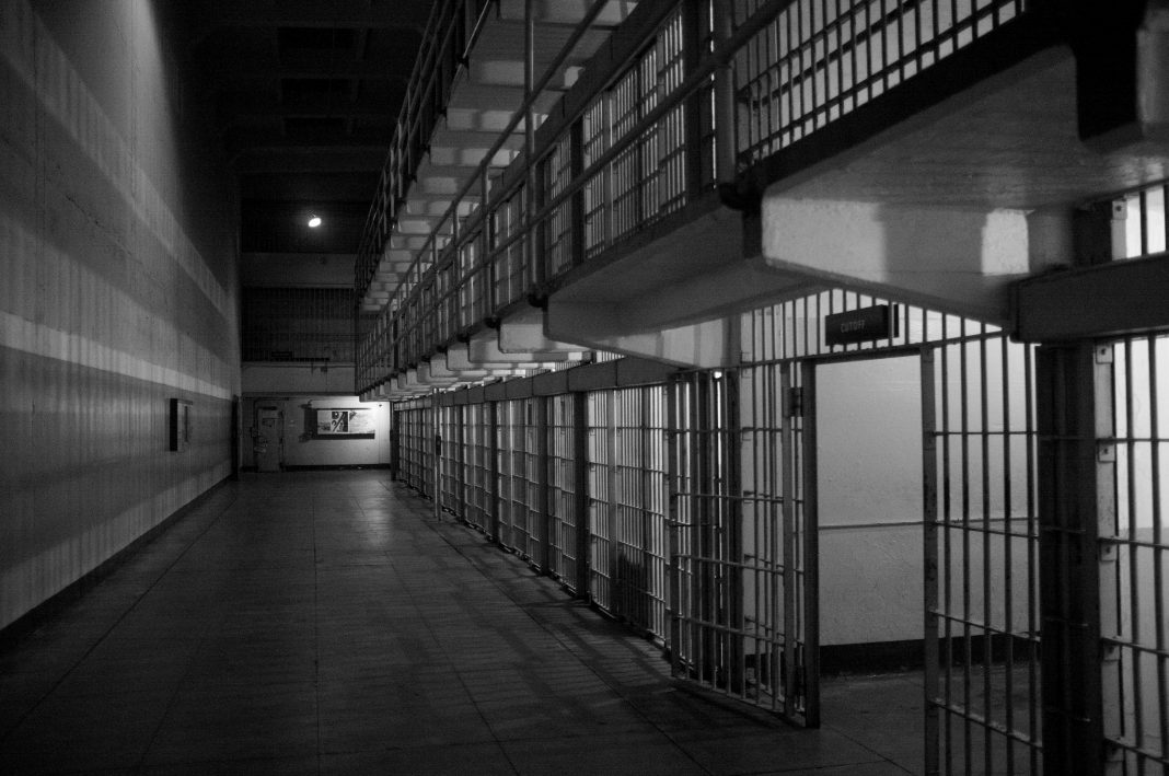 Black and white photo of open prison cells. | Unsplash/Emiliano Bar