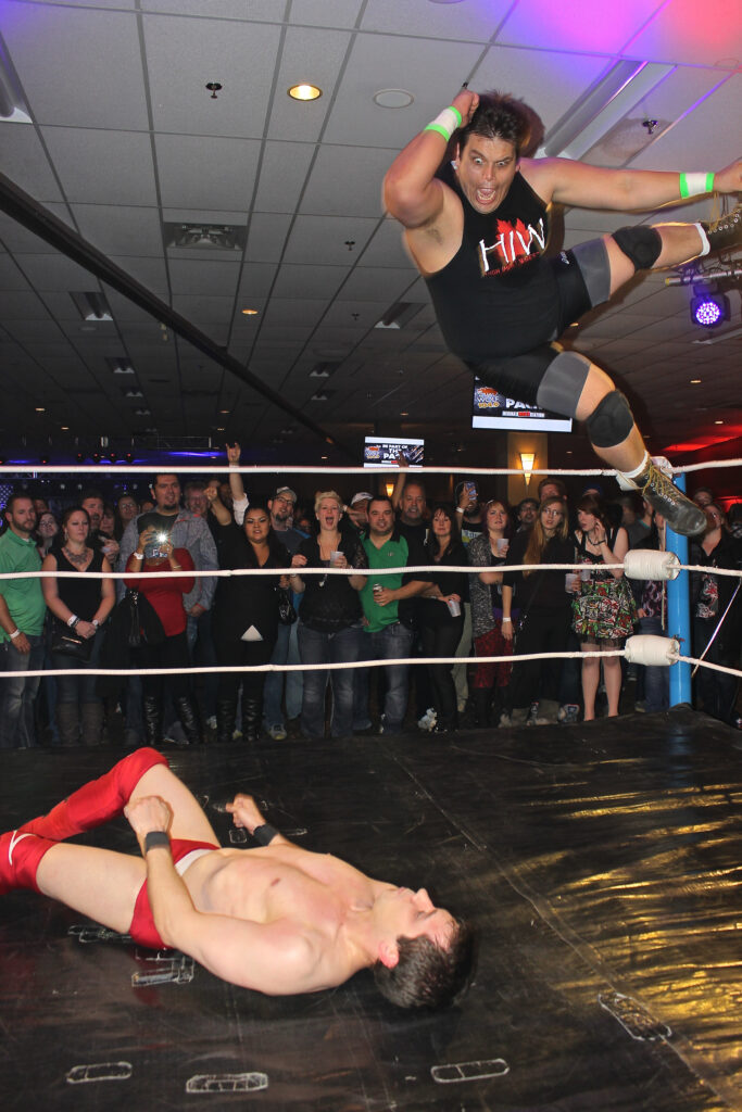 Thyrillin Dylan dropping the elbow from the top rope on motionless Jeff Taylor in Regina, 2015.